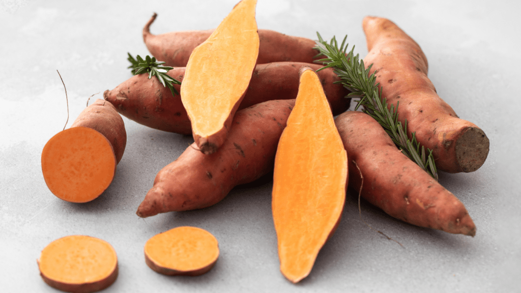 a pile of sweet potatoes with sprigs of rosemary