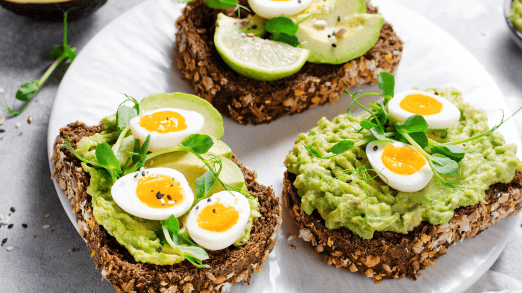 avocado toast with eggs and avocado on a white plate