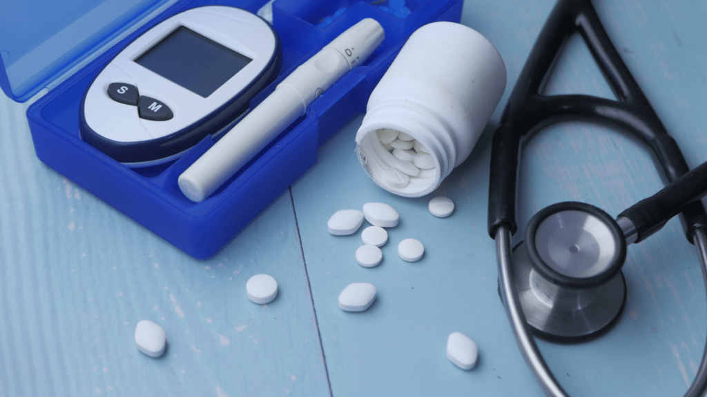 a stethoscope, pills and a glucose meter on a blue table