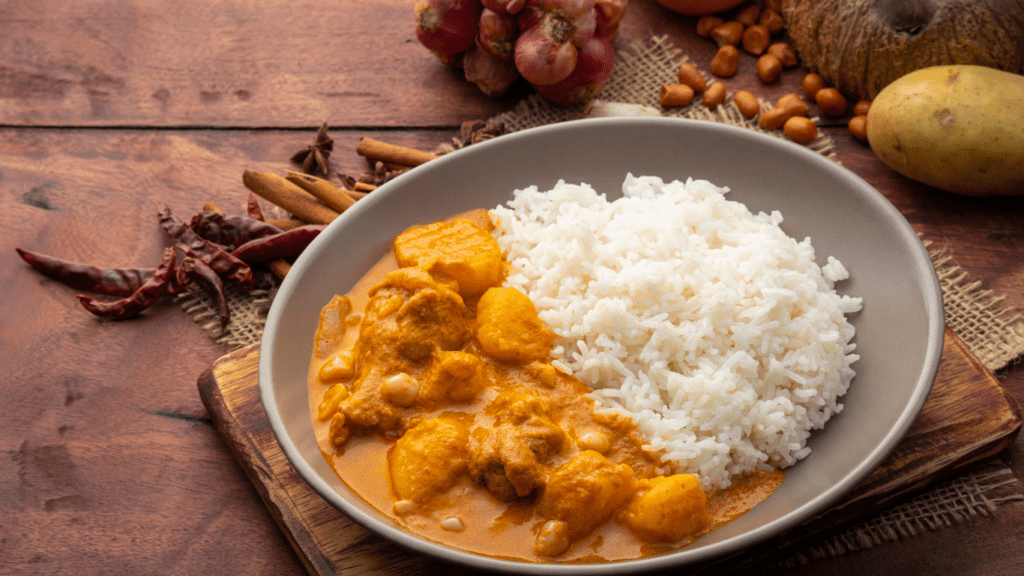 chicken curry in a bowl with rice on a wooden table