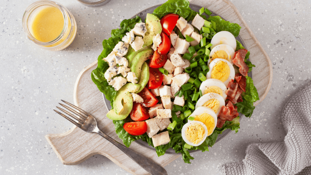 a salad with chicken, eggs and avocado on a plate