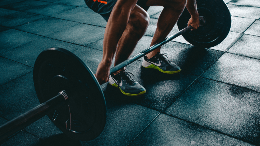 a person is squatting with a barbell in a gym