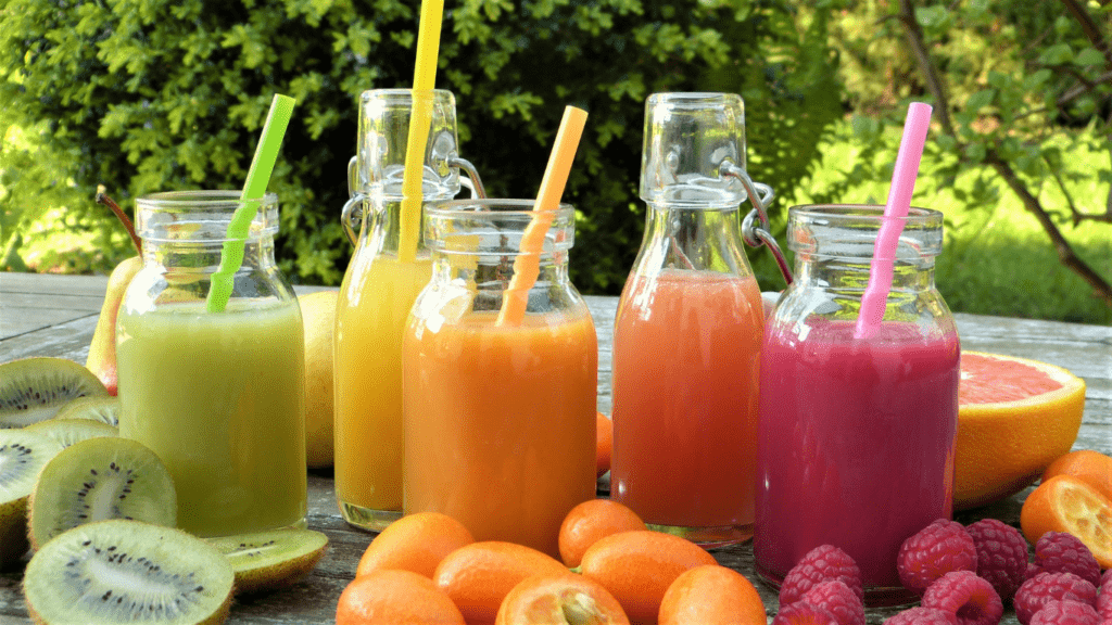 various fruit juices in glass bottles on a wooden table