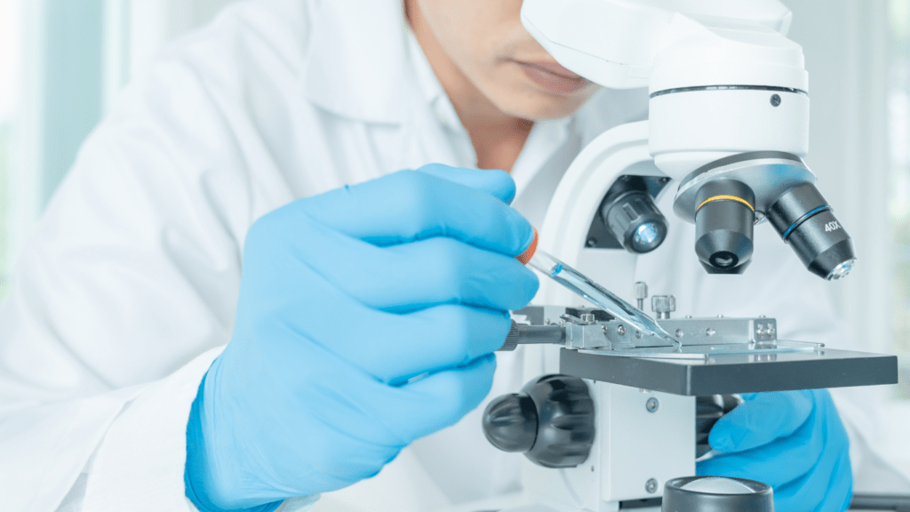 a person in a lab coat is looking through a microscope