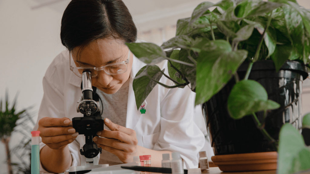 a person in a lab coat is looking through a microscope