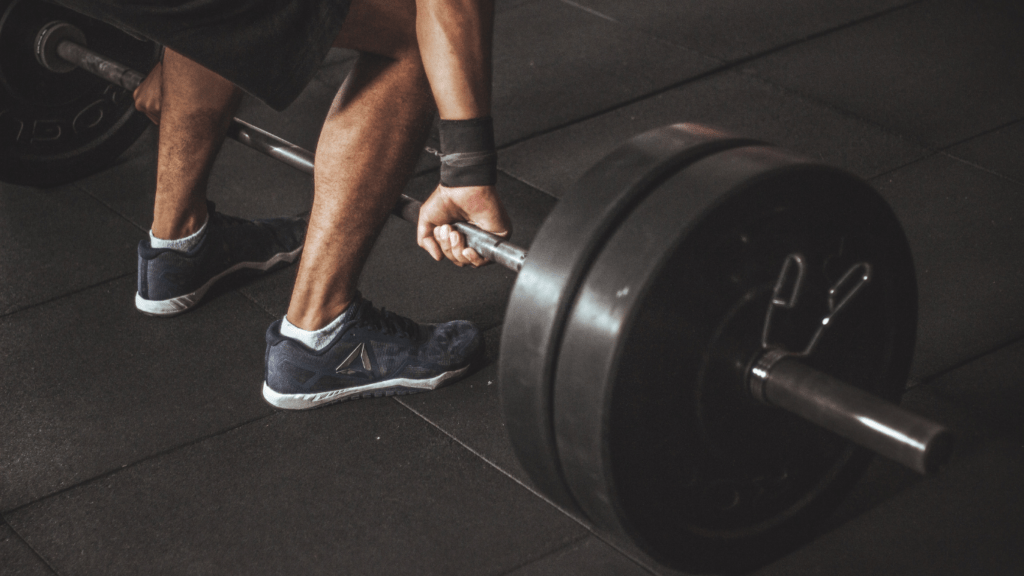 a person is squatting with a barbell in a gym