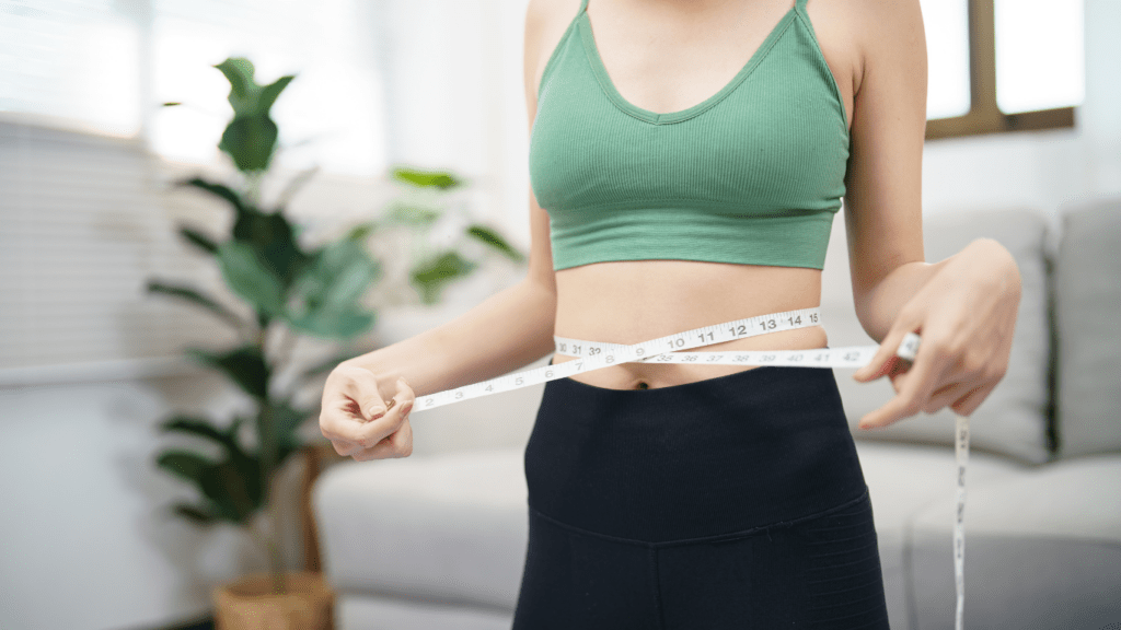 a person measuring their waist with a tape measure