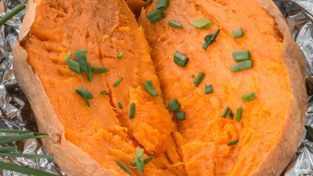 a pile of sweet potatoes with sprigs of rosemary