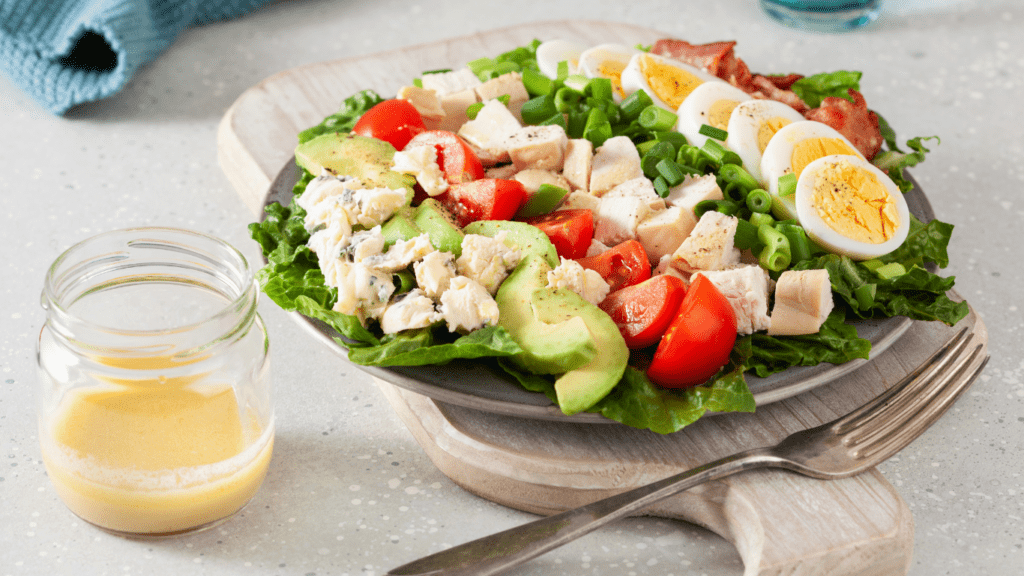 a salad with chicken, eggs and avocado on a plate