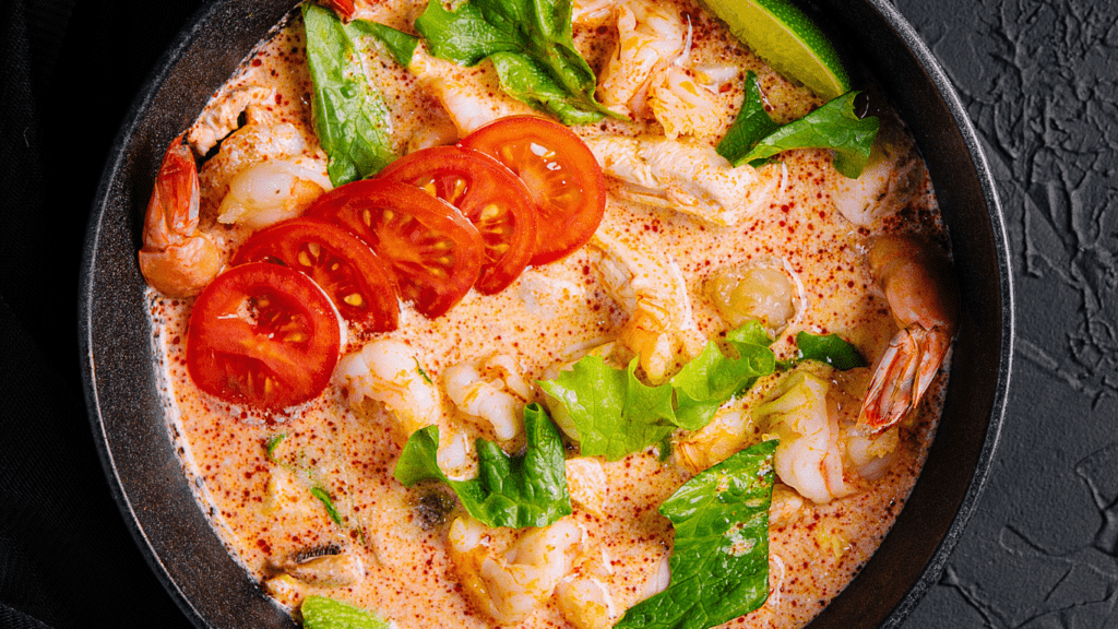 chicken curry in a bowl with rice on a wooden table