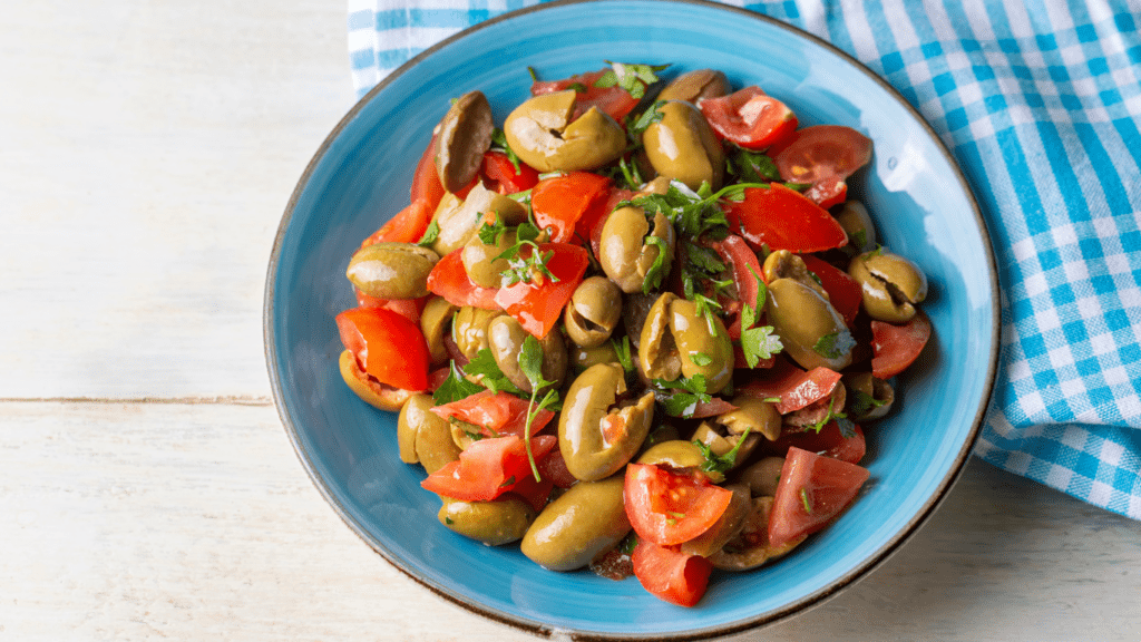 salad with olives and tomatoes in a blue and white bowl on a wooden table