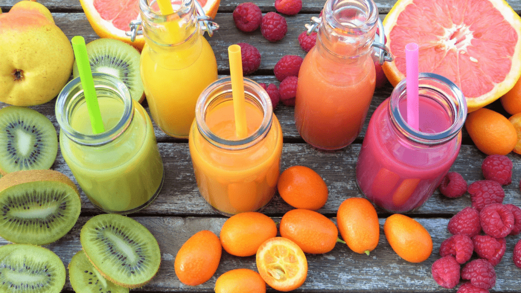 various fruit juices in glass bottles on a wooden table